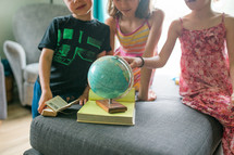 children studying a globe 