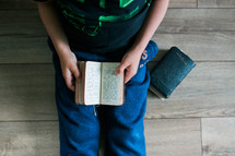 a boy reading from an old Bible 