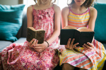 two girls reading from old Bibles 
