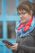 a woman listening to earbuds and holding a tablet 