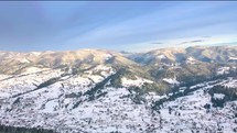 Aerial view of snowy mountains and village in winter 4k