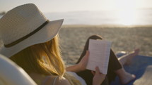 young attractive woman sitting on a beautiful beach reading a book