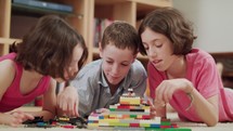 Three kids playing with toy plastic bricks at home