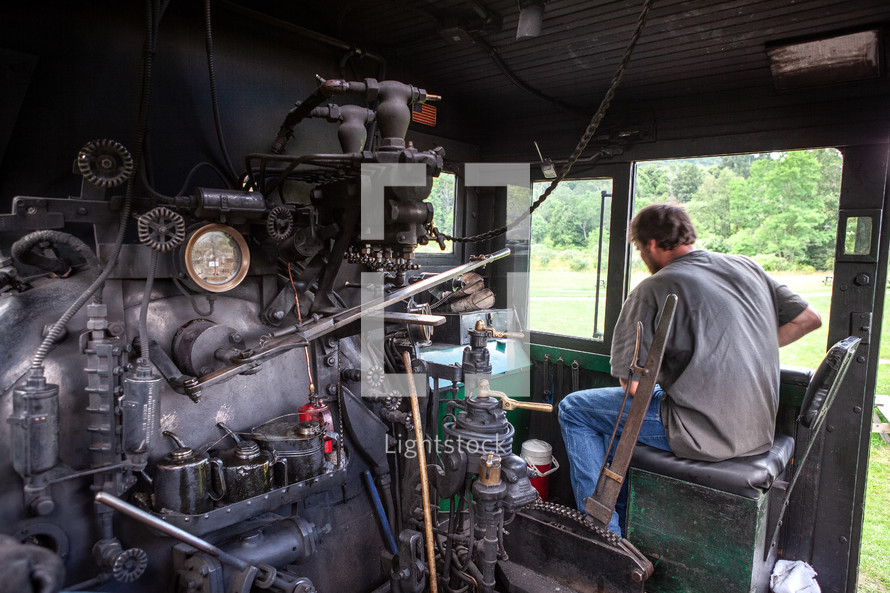 Man in control area of old steam train locomotive