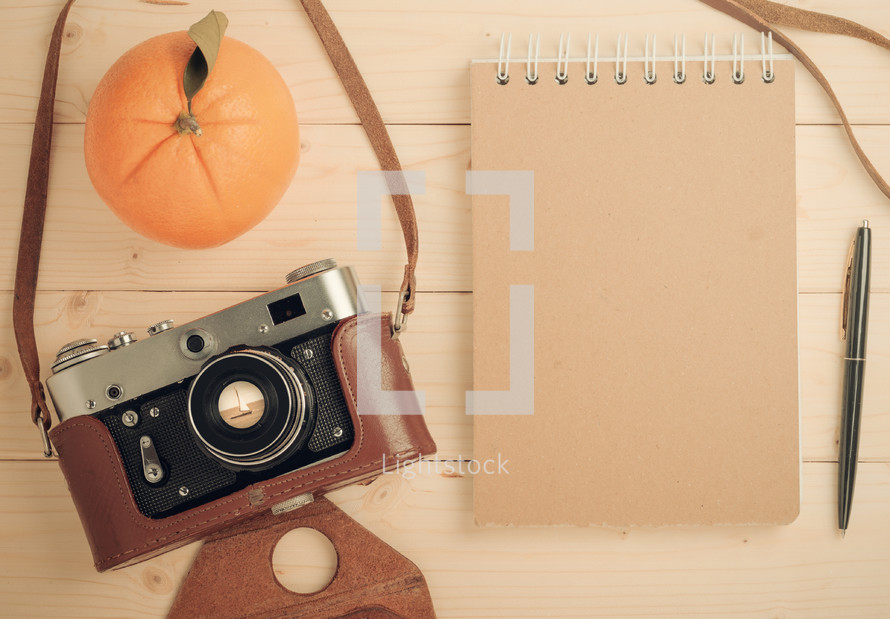 orange, camera, notepad, and pen 