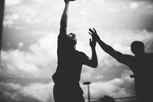 Silhouette of men playing basketball.