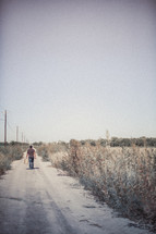 man walking down a dirt road with luggage 