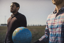 two men holding a globe in a field 