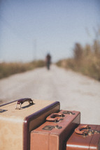 luggage and a man walking down a dirt road 