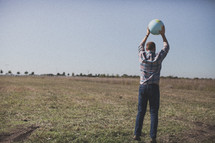 man in a field holding a globe 