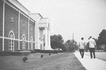 men walking down a sidewalk heading to church
