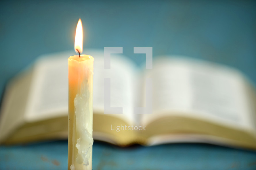 melting candle in front of an open Bible 