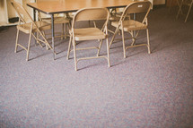chairs under a table in an empty classroom