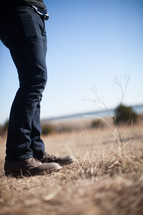 legs of a man standing outdoors on winter grasses 