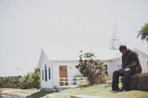 man in prayer outside of a church 