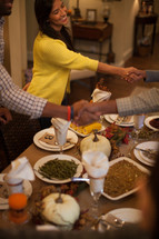 shaking hands in greeting and welcome at a Thanksgiving dinner table 