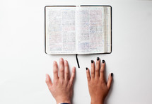 open Bible and hands on a table 