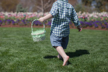 Young boy holding an Easter basket, walking in a garden of  flowers