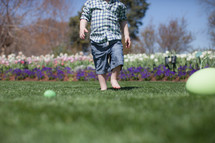 young child looking for Easter eggs in a garden of flowers