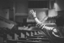 hands raised in worship to God inside an empty church