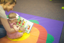 nursery staff and and infant reading a book