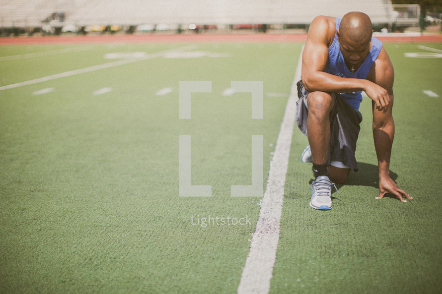 athlete kneeling in prayer on the football field 