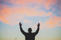 silhouette of a man with his hands raised to God 