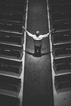 man standing in the aisle of a church with his arms raised in praise to God
