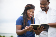 happy African-American couple reading a Bible together outdoors 