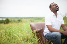 man looking to God in prayer sitting in a chair outdoors 