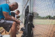 men praying in a baseball dugout 