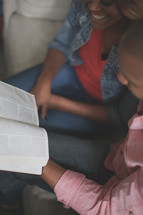 couple reading a Bible together on a couch 