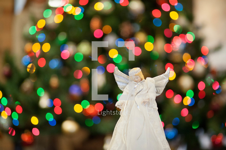 angel ornament in front of bokeh Christmas lights 