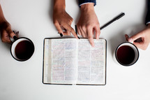 looking down at an open Bible and coffee mugs at a Bible study 