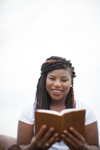 a woman reading a Bible smiling 