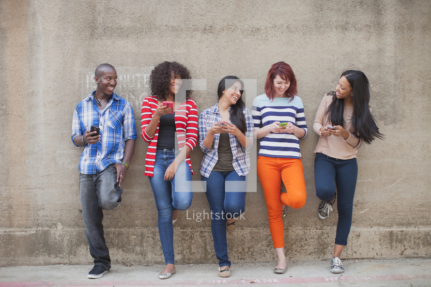 a row of young adults checking their cellphones 
