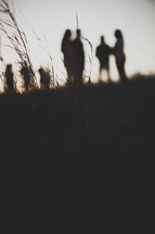 groups gathered outdoors talking in a field at sunset 