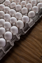 Cartons of white eggs on a wood table.