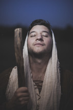 face of a shepherd holding his staff with closed eyes praying 
