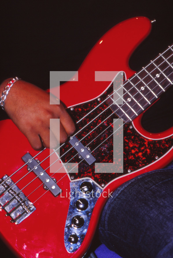 African American man's hand on a red electric guitar 