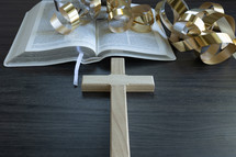 cross, gold streamers and open bible on a dark wood background