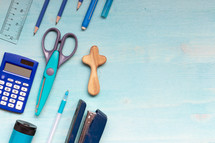 border of school supplies on a teal wood desk 
