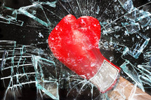 fist in a boxing glove breaking glass 