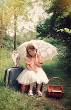 A girl with an umbrella and suitcases and an owl in a forest 