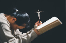 Asian woman holding a crucifix and Bible
