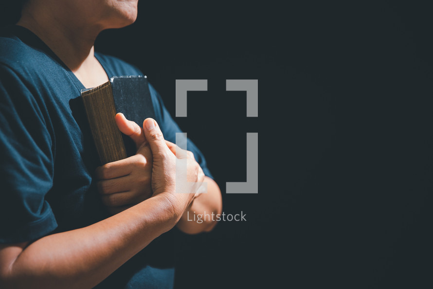 Hands folded over a Bible