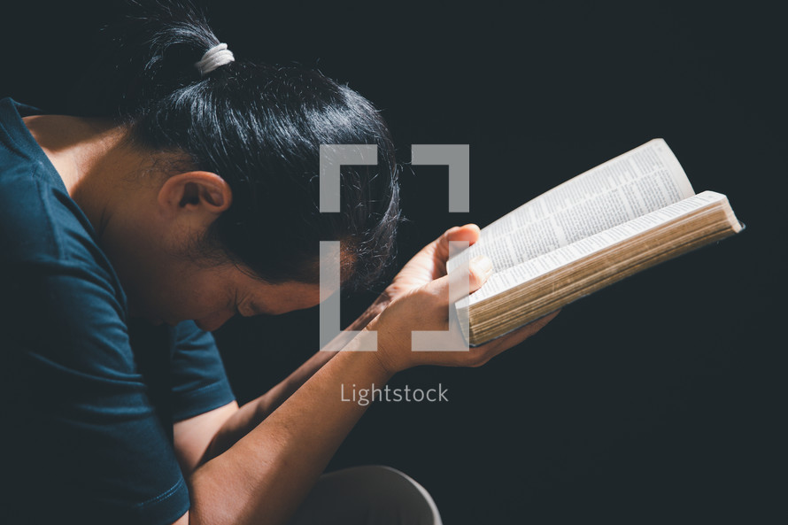 Asian woman praying with bible