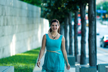 a woman in a blue dress walking down a sidewalk 