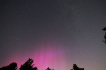 Night sky with some pillars of pink Aurora Borealis 