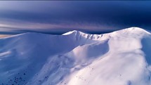 Aerial view of snow covered mountain range at dusk 4K drone shot